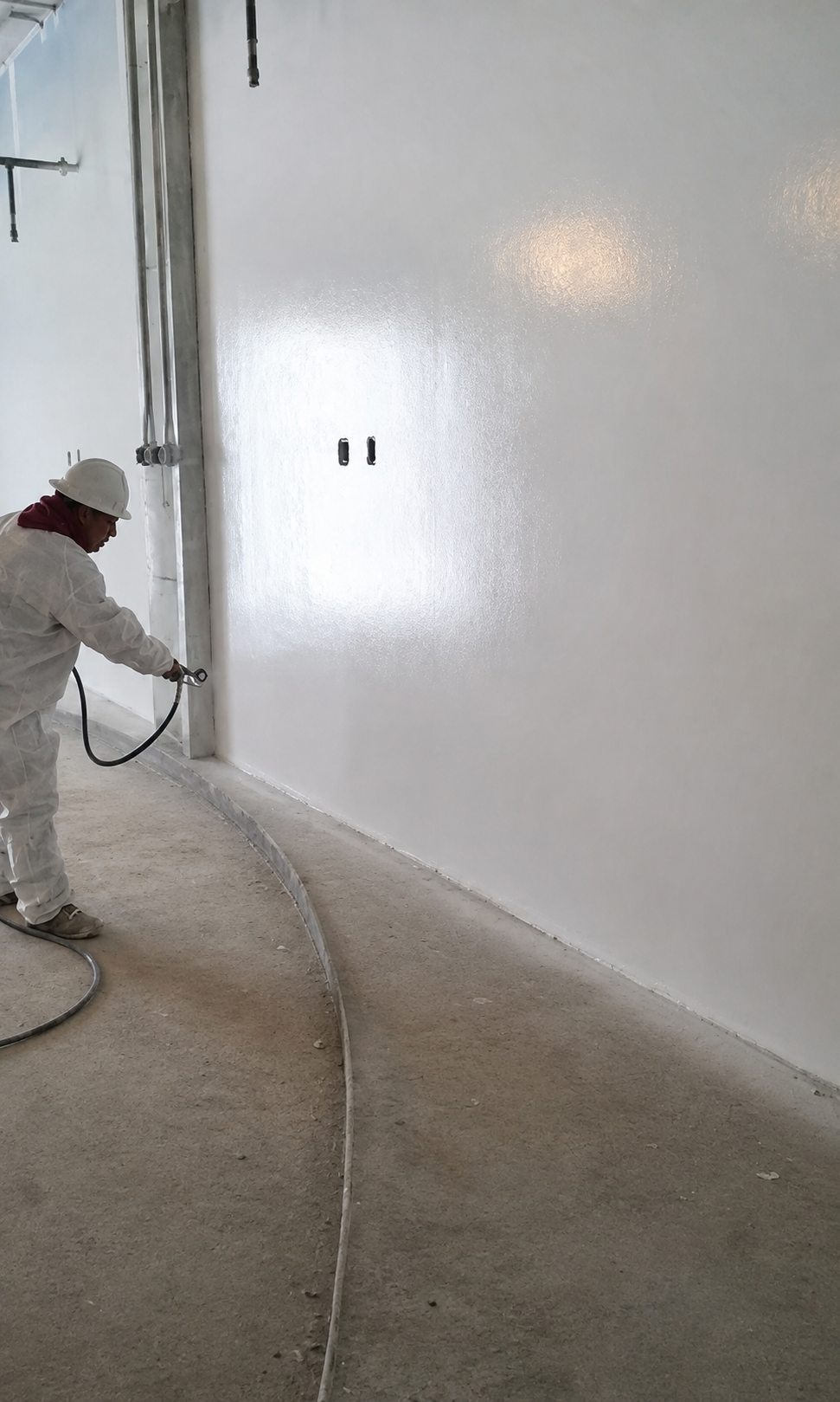 Finisher spraying coating on a long commercial wall