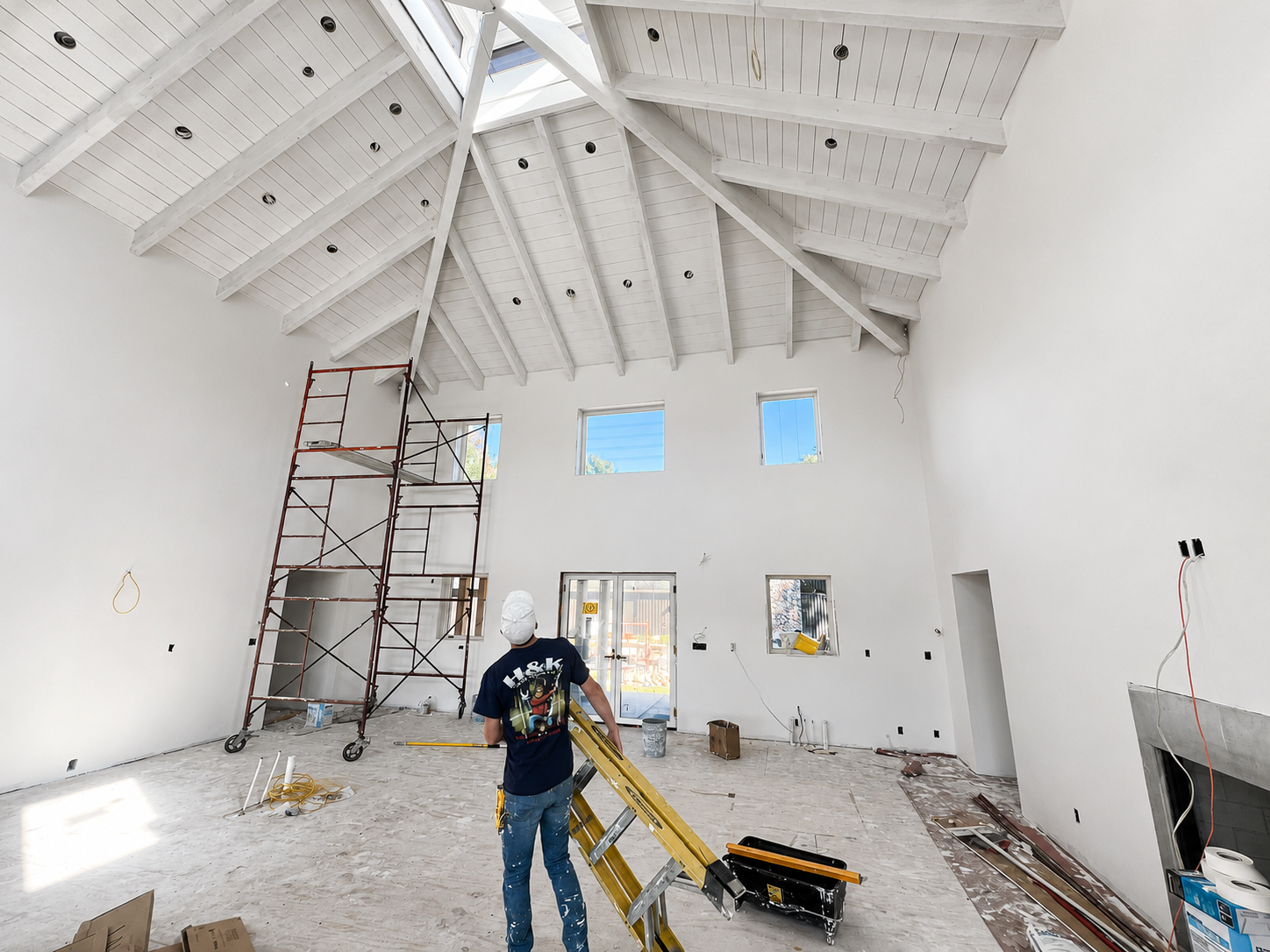 H&K team member working in a vaulted great room with finished drywall and painted rafters